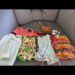 assortment of american girl doll clothes and hairbrush